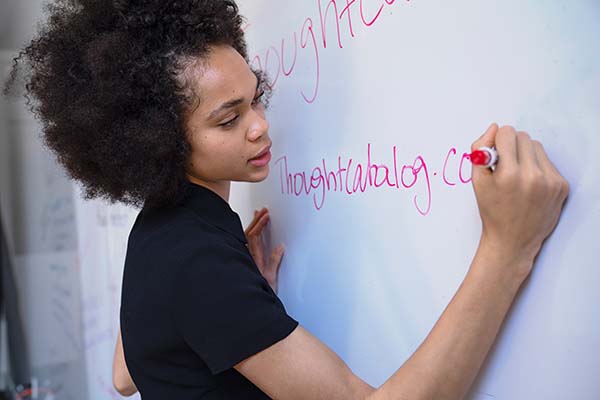 Eine junge Frau notiert die Zurufe von Teilnehmern des 
                Dynamic Facilitation Workshops auf einem Whiteboard